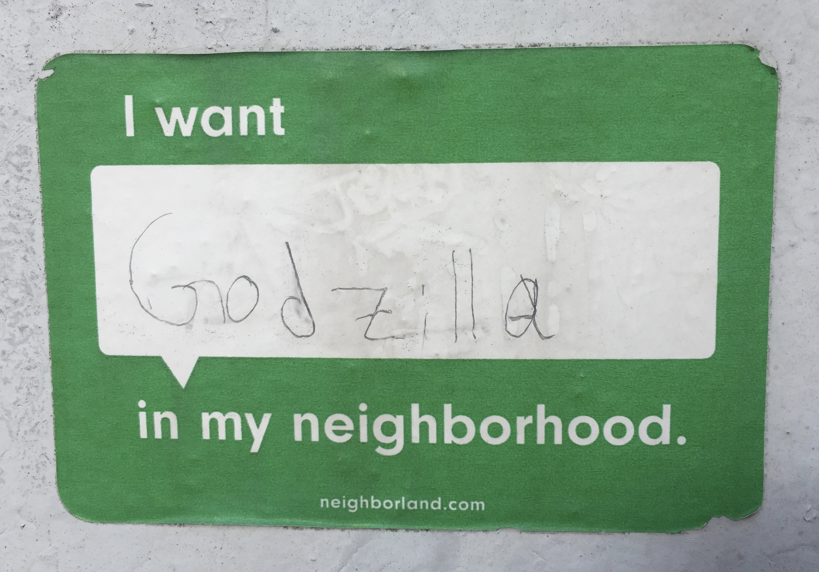 A sticker from neighborland.com: "I Want Godzilla in my neighborhood." WIth a child's block letters.