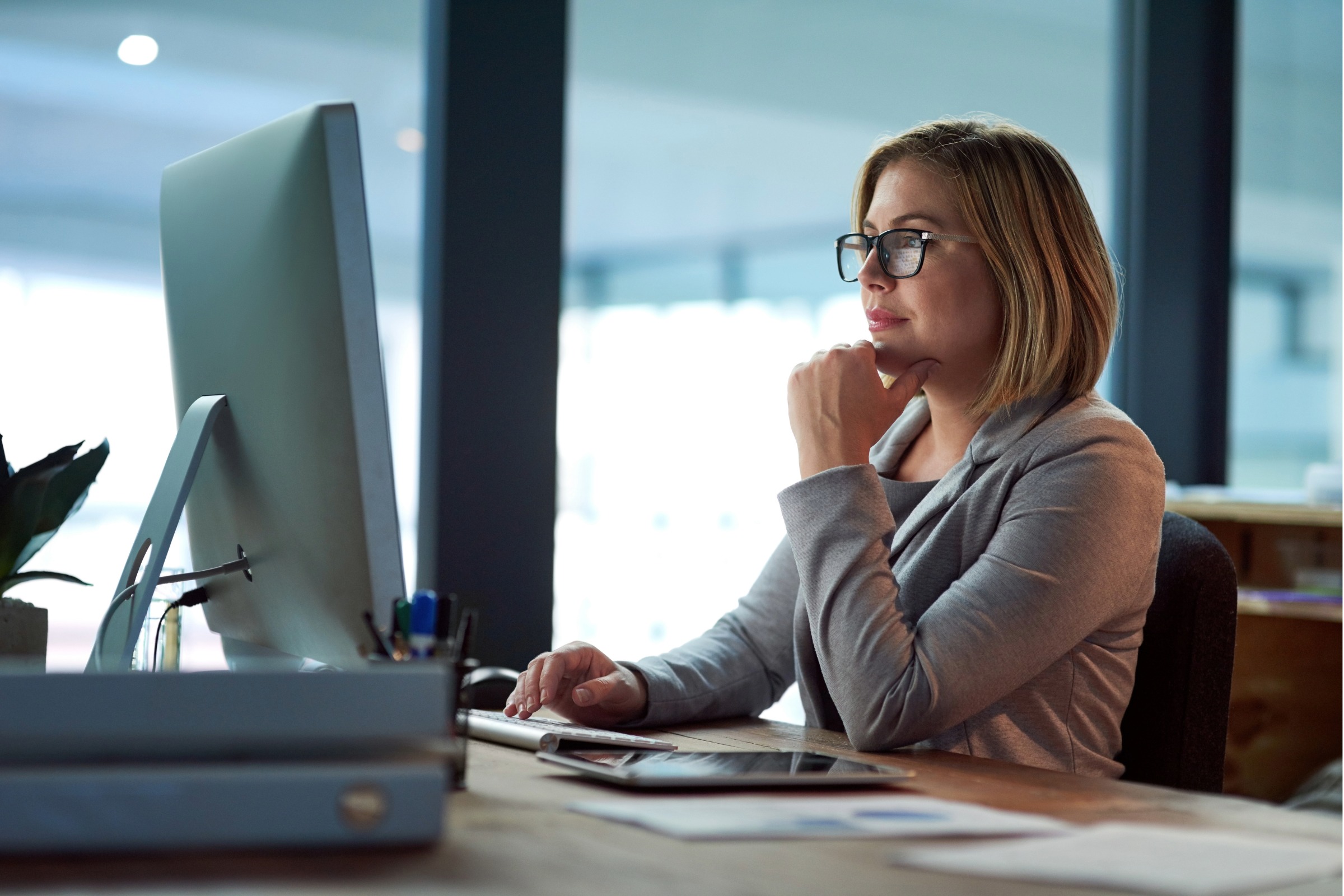 A woman is writing at her computer.