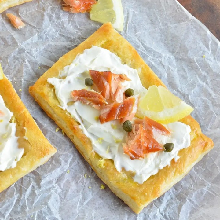 This Easy Smoked Salmon Appetizer Recipe begins with flaky puff pastry, topped with cream cheese, smoked salmon, lemon, capers and fresh dill. Perfect for an appetizer or breakfast!