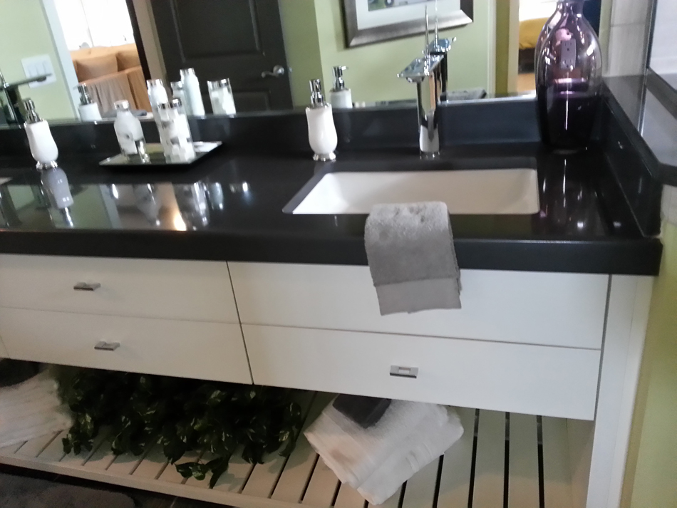 Custom vanity with white painted slab doors, open storage and absolute black top.