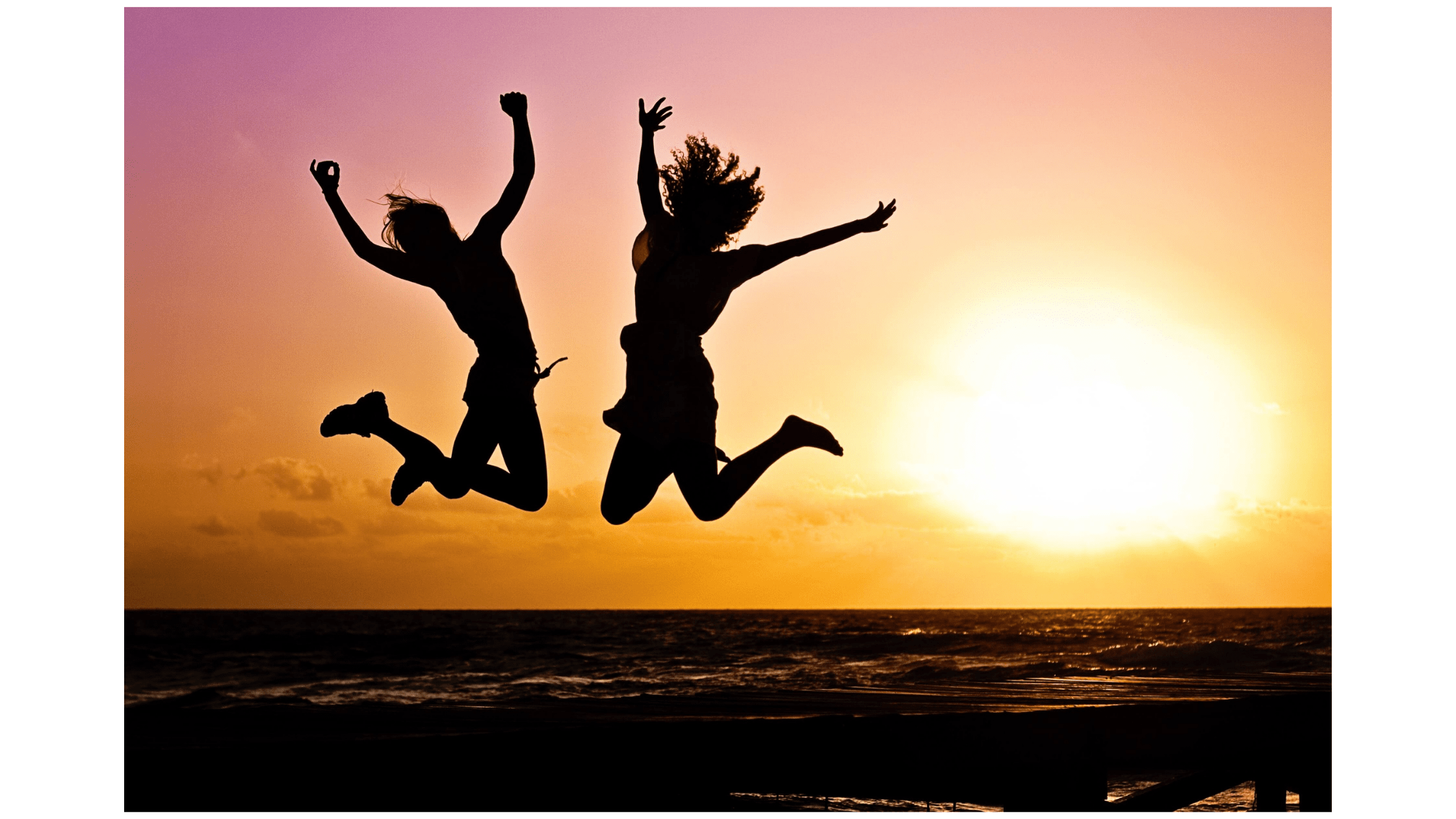 Two people jumping for joy. They are silhouetted against a sunset.