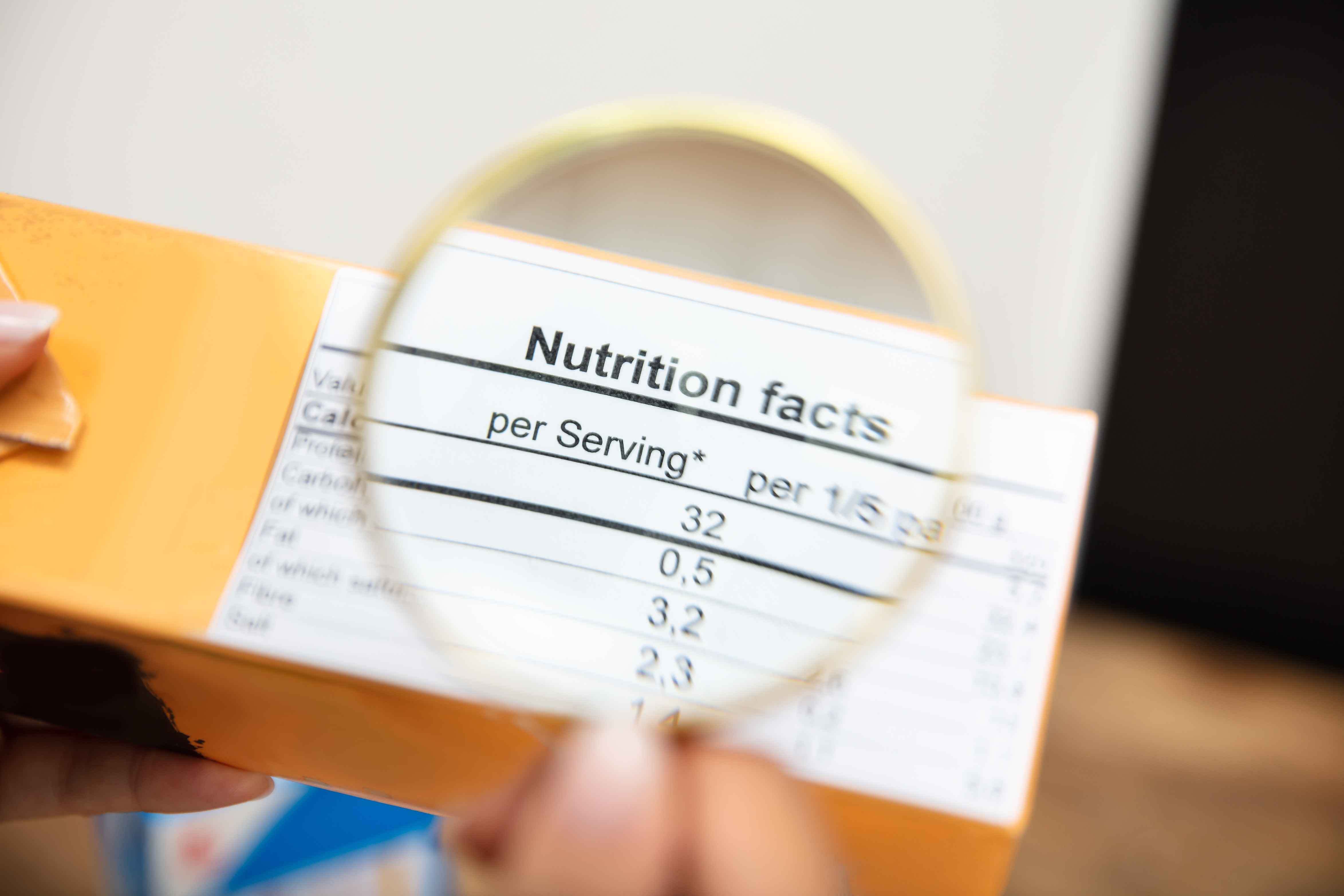 A Person Looking Nutrition Facts On Package Through Magnifying Glass. Understanding food labels. Nutrition.
