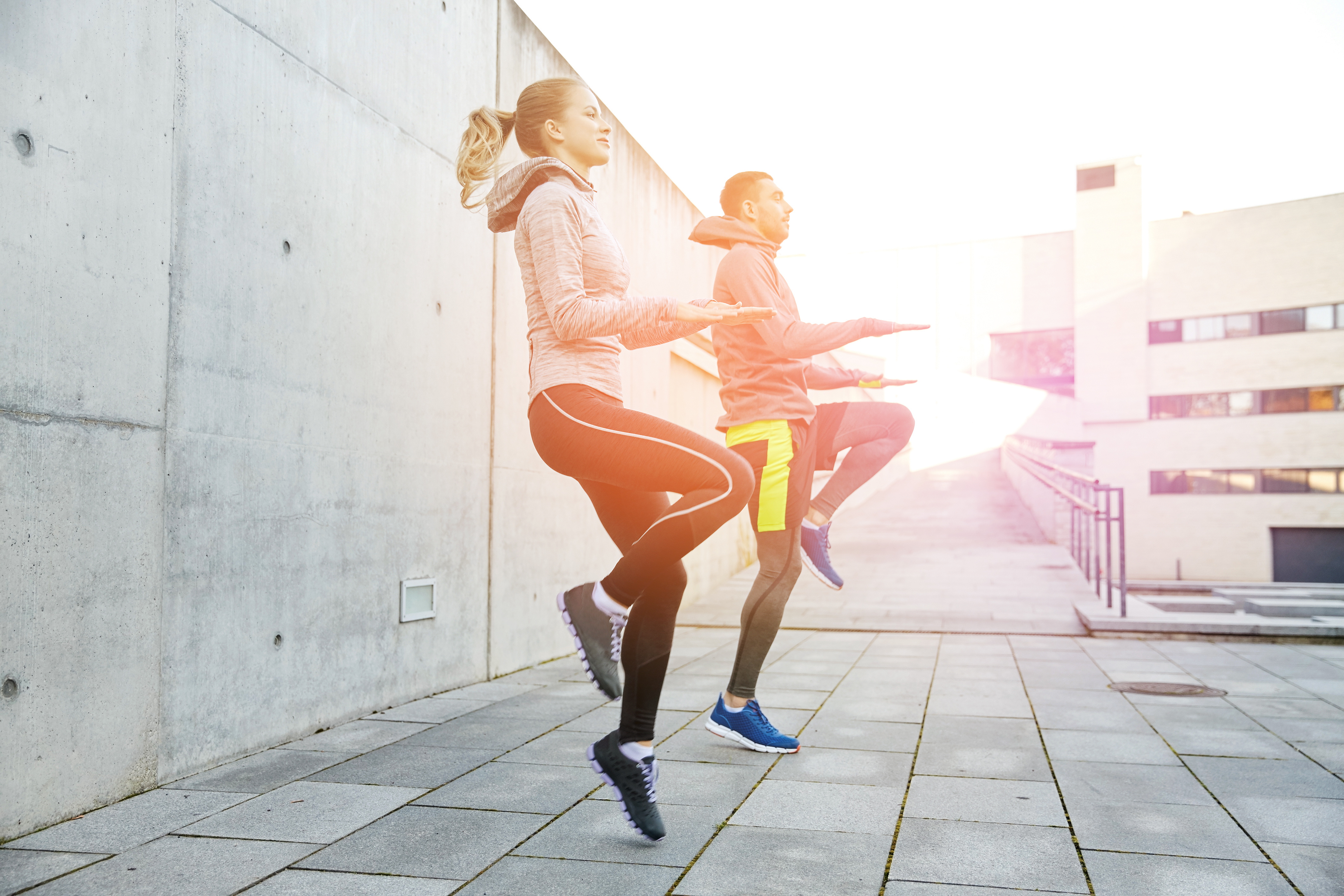 balance matters for longevity fitness, sport, people, exercising and lifestyle concept - happy man and woman jumping outdoors