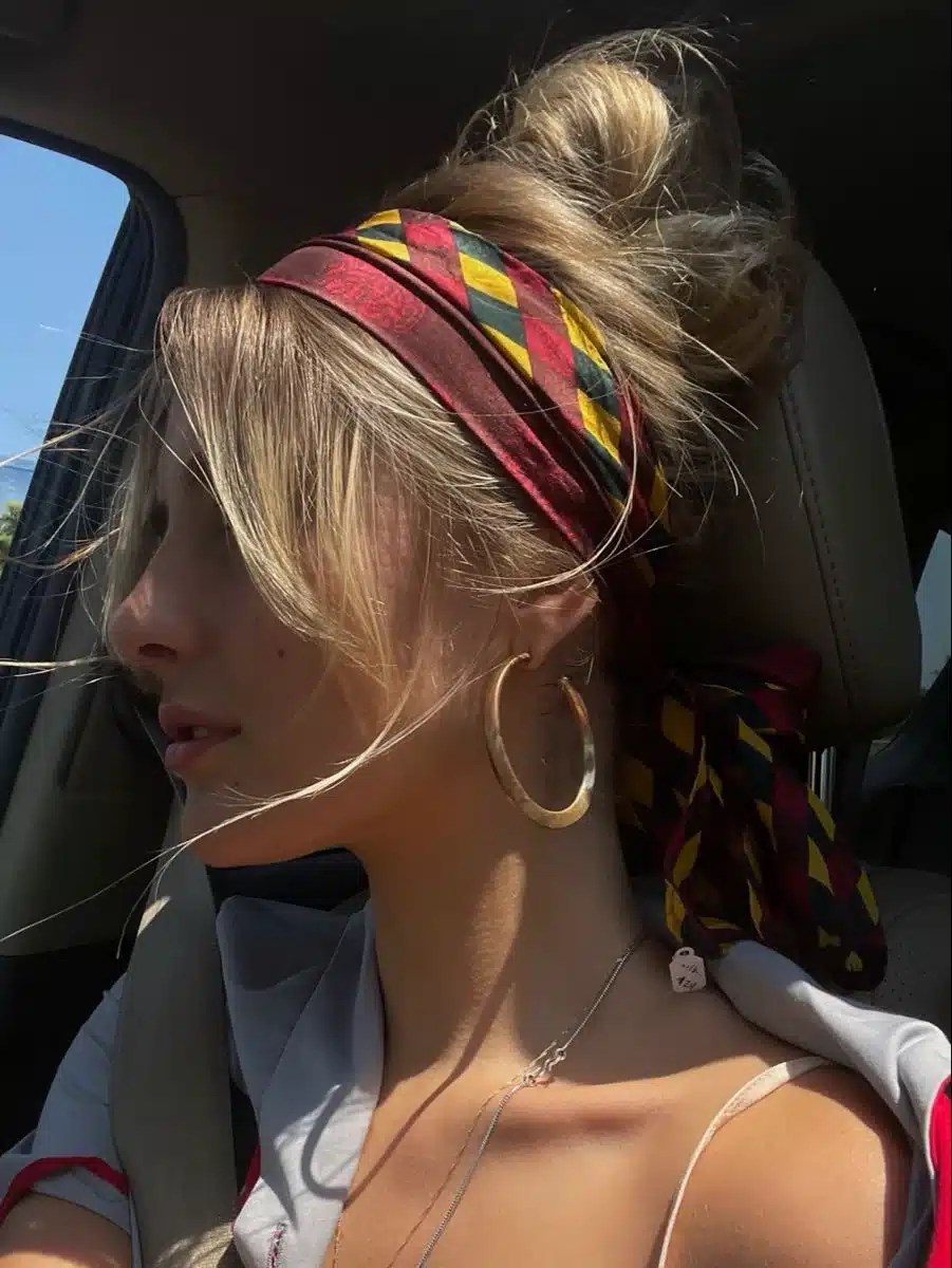 Messy bun hairstyle styled with a bandana headscarf, creating an effortless pool hairstyle that's perfect for protecting hair during summer holidays and beach trips.