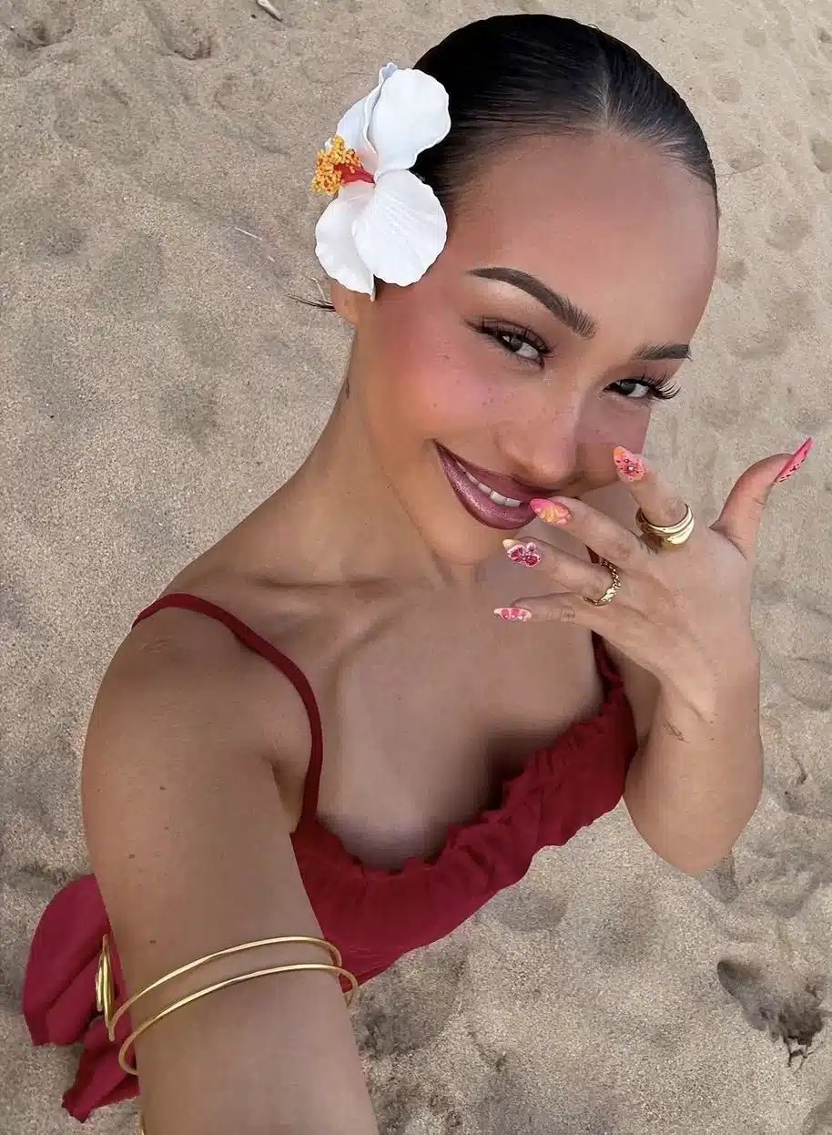 Sleek low bun hairstyle finished with a flower accessory, creating an elegant beach hairstyle that's perfect for holidays, swimming, and warm summer weather.