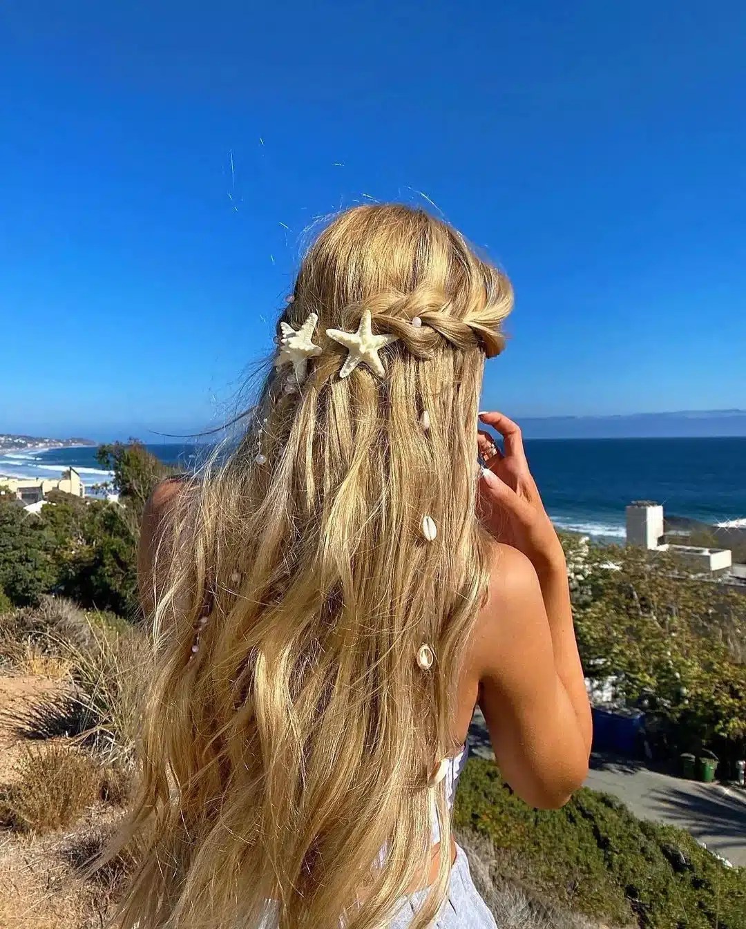 Long mermaid waves styled with decorative shell hair clips, creating a beach-inspired summer hairstyle that's perfect for pool days, seaside holidays, and tropical vacations.
