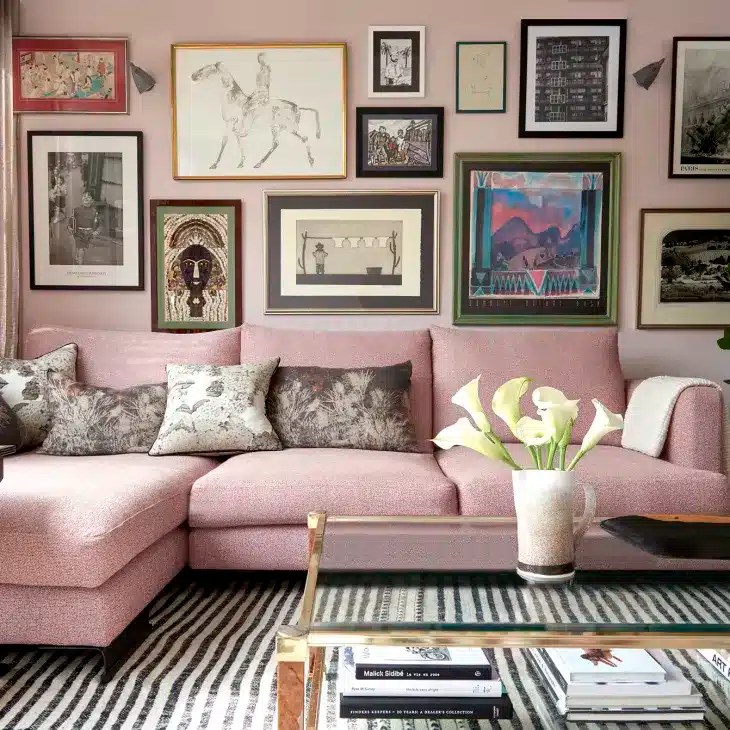 A colorful open-plan living room featuring a large pink sofa, patterned cushions, framed artwork, indoor plants and warm neutral flooring in a modern London home.
