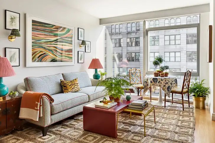 A colorful eclectic living room featuring a pink velvet armchair, statement artwork, indoor plants, layered textiles, neon lighting and vintage accessories in a modern family home.