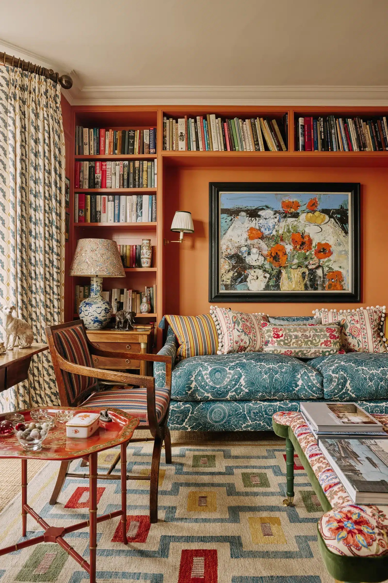 A colorful living room featuring emerald green walls, velvet seating, framed artwork, layered lighting and decorative accessories that create a rich, luxurious interior.
