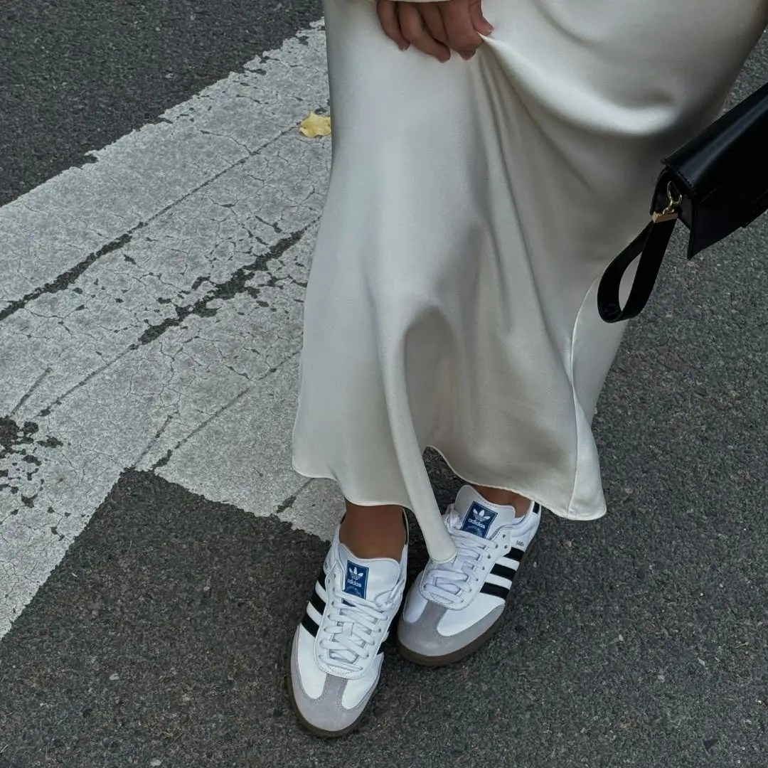 Style Wellness And Confidence inspiration featuring a cream satin slip skirt styled with Adidas trainers and a minimalist black handbag for an elevated everyday look