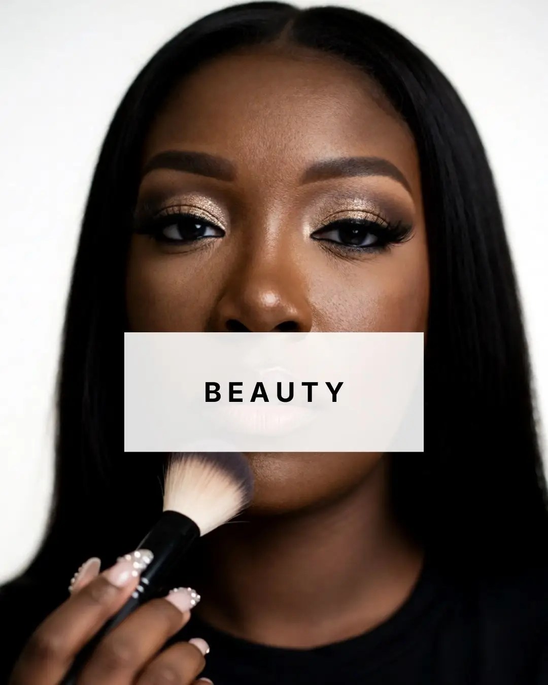 Wots Her Name Again beauty featuring a Black woman applying makeup with glowing skin and neutral eye makeup.