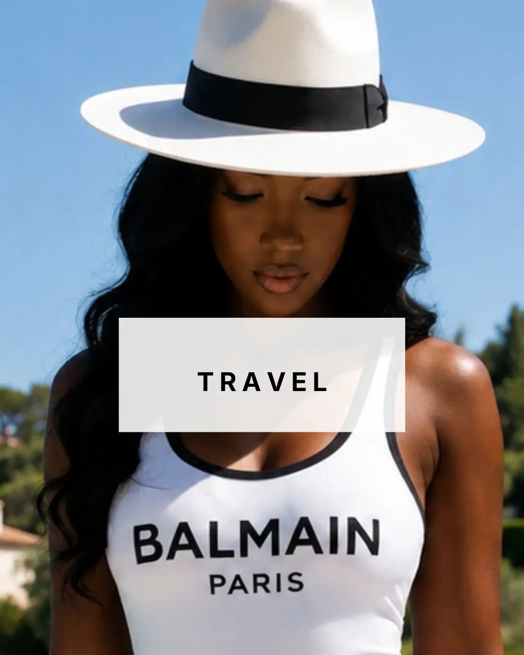 Wots Her Name Again travel featuring a Black woman in a white sun hat and monochrome holiday outfit.
