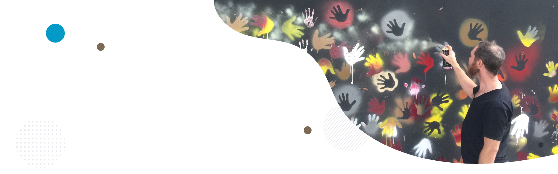 A man spray painting a black wall with hand prints