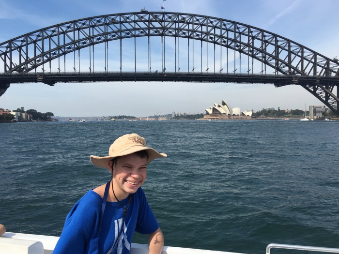 Gage on the ferry to Darling Harbor with the Opera House and Harbor Bridge behind him.