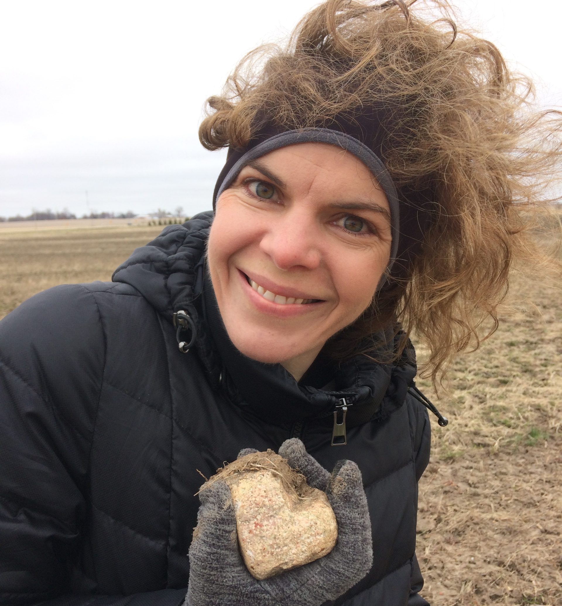 Woman smiling holding sufficient grace heart-shaped rock