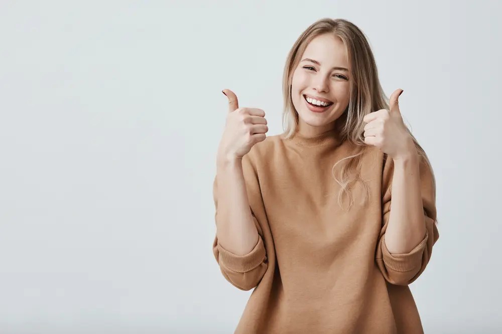 Smiling woman giving two thumbs up after receiving mobile phone repair service in Glenolden, PA