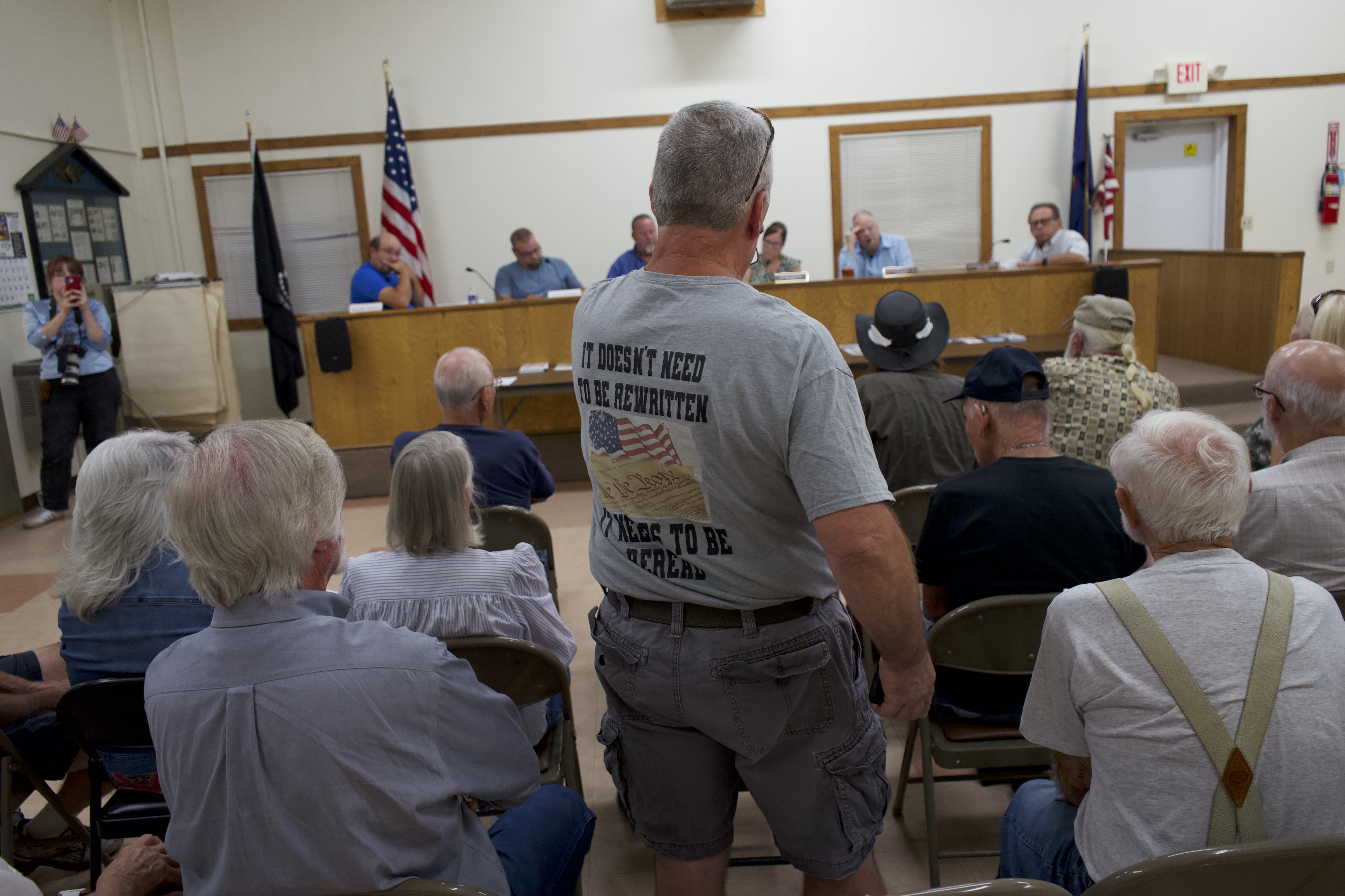 A man stands up in a meeting room to speak.