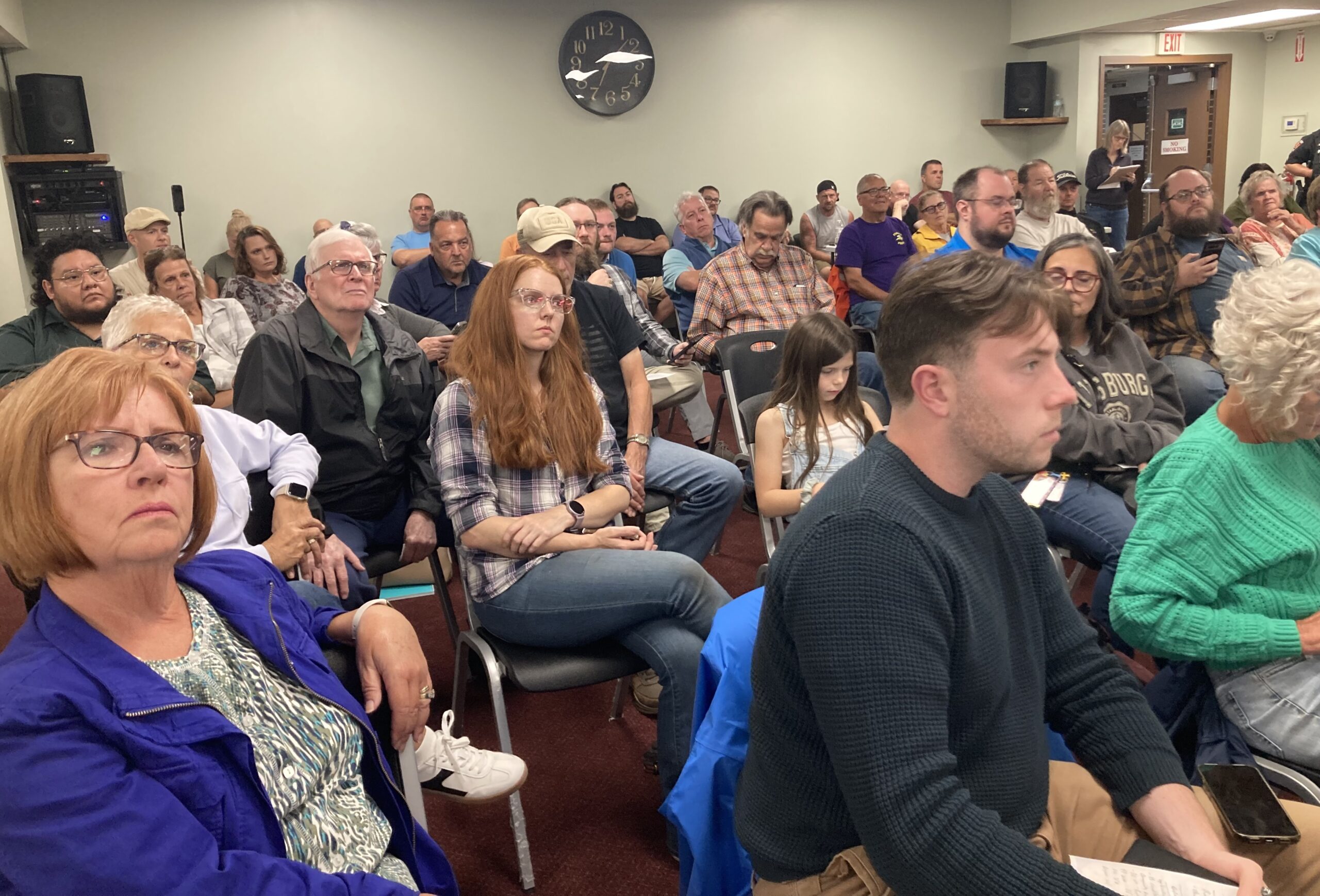 People sit on folding chairs in a large conference room