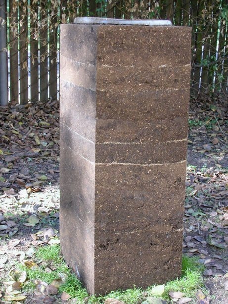 Rammed earth pedestal with ice on top, outside.