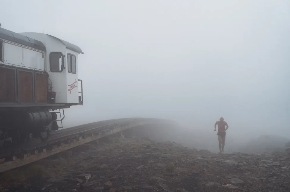 A runner beside the Cog train in the summit fog