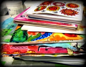 Stack of colorful sketchbooks and notebooks with vibrant drawings and doodles on a table, inspiring creative minds to think.