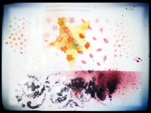 A colorful abstract design featuring a central yellow star, various dots, floral patterns, and smudges.
