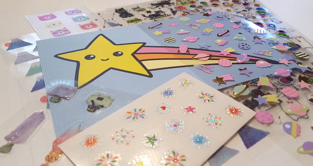 Colorful craft stickers from Pipsticks, featuring a smiling shooting star, planets, and various small shapes, spread out on a table.