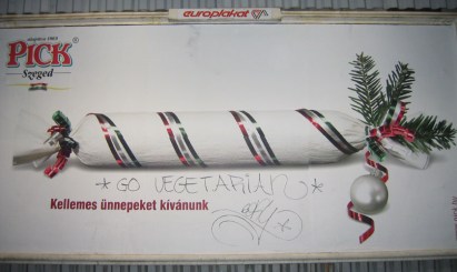 An ad for salami with graffitti that says "go vegetarian"