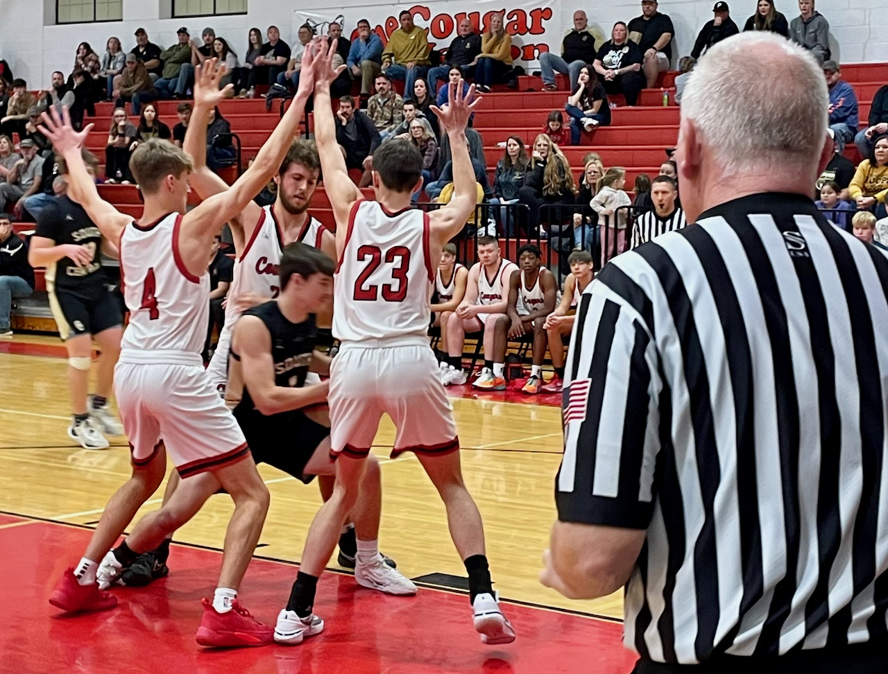 A basketball player his surrounded by three defenders