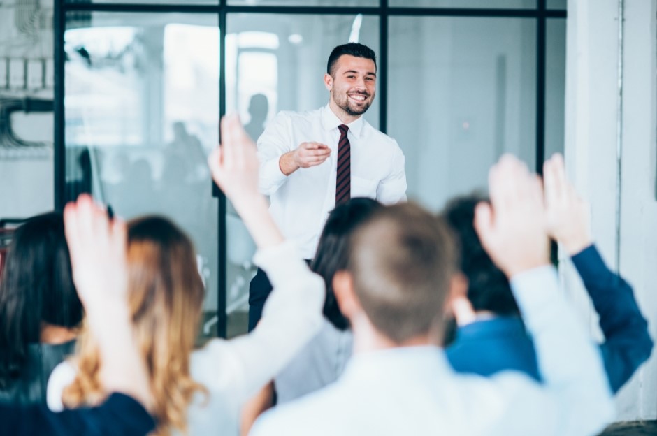 Un docente che indossa una camicia e una cravatta bianca sta svolgendo una lezione con degli alievi adulti. Consulenza Formazione e Finanza agevolata
