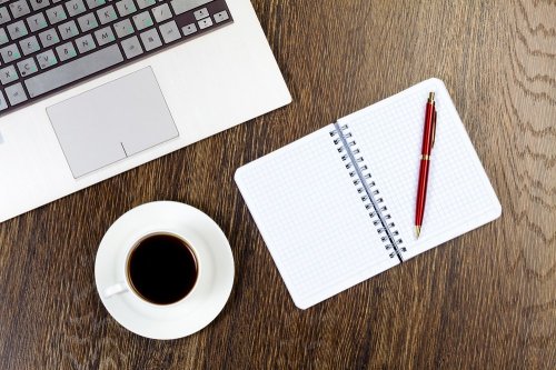 Tablet pc cup of coffee and notepad at table