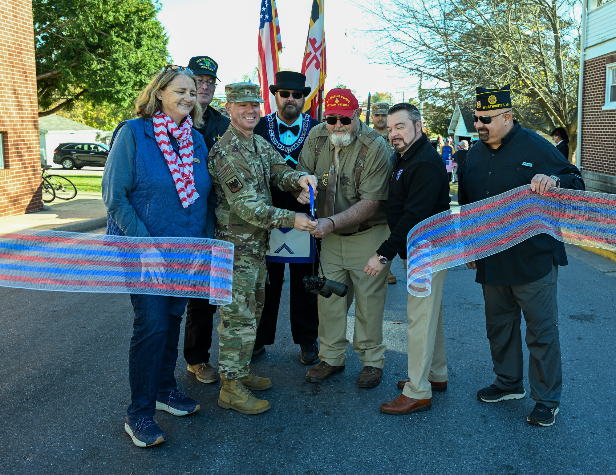 Westminster Mayor Mona Becker, from left, Jason R. Sidock, Executive Director Veterans Independence Project, Masonic Lodge Master Mike Pennington, Commissioner Tom Gordon III and Council Member Tony Chiavacci watch as Grand Marshal Brig. Gen. Reid Novotny and Honorary Grand Marshal Ed Starrett cut the ribbon before the first annual Veterans Day Parade in Westminster.(Karen Jackson/Freelance)