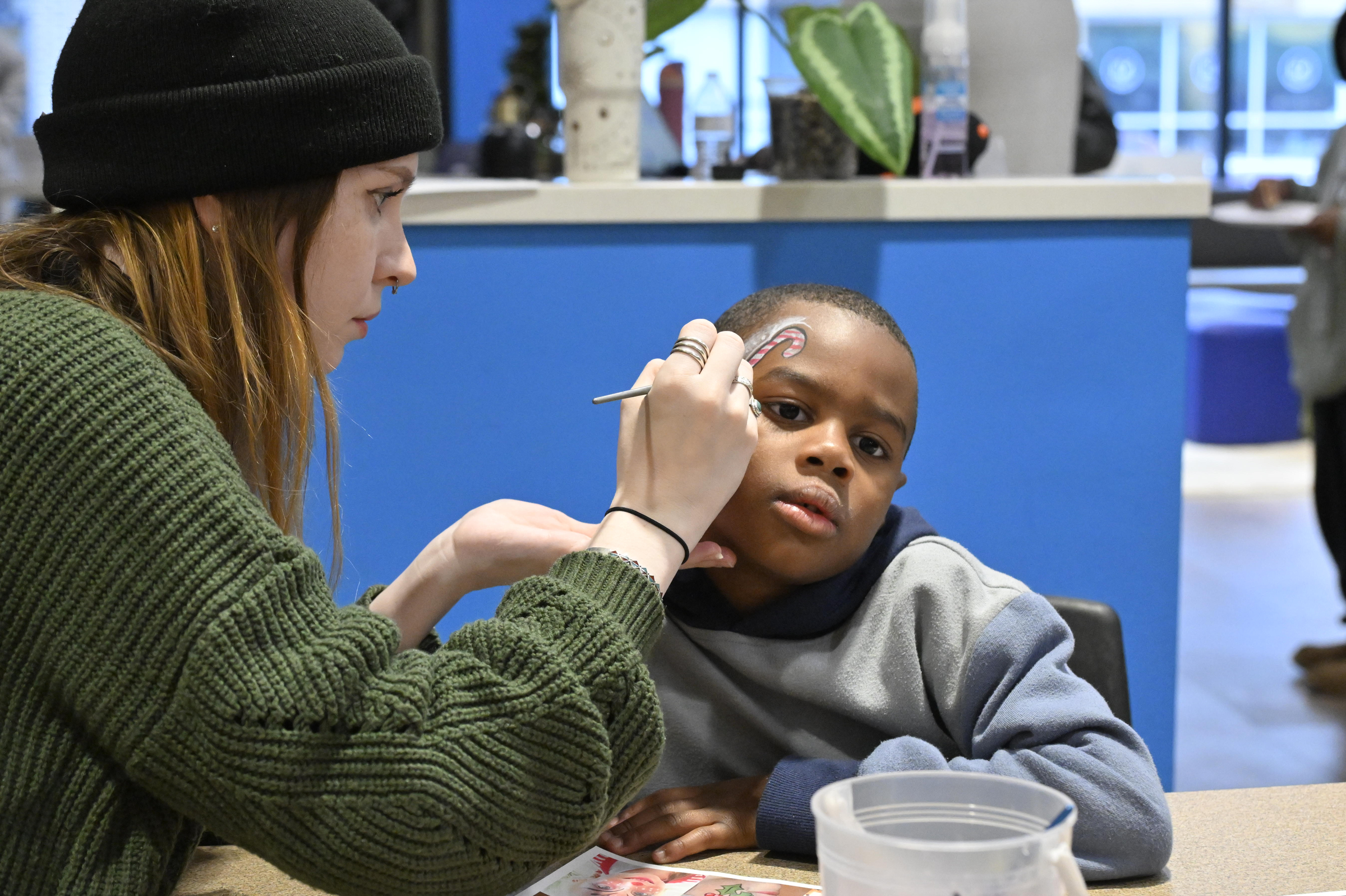 McDaniel student Emma Lavis paints the face of Zhayne Thomas,6, at the Boys and Girls Club annual holiday party in Westminster.(Thomas Walker/Freelance)