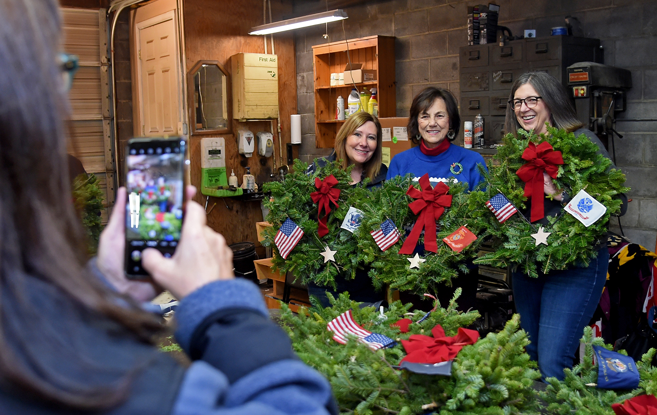 Volunteers pose for a photo. Left to right: Lisa Haggerty of Hampstead, Peggy Ludwig of Marriottsville and Patti Wall of Mt. Airy. The volunteers decorated ceremonial wreaths with military branch flags and stars this morning at Babylon Vault Company in New Windsor. The wreaths were provided by Wreaths Across America, and will be placed on the graves of veterans in 47 cemeteries. Today, the volunteers decorated 376 wreaths. (Barbara Haddock Taylor/Staff)