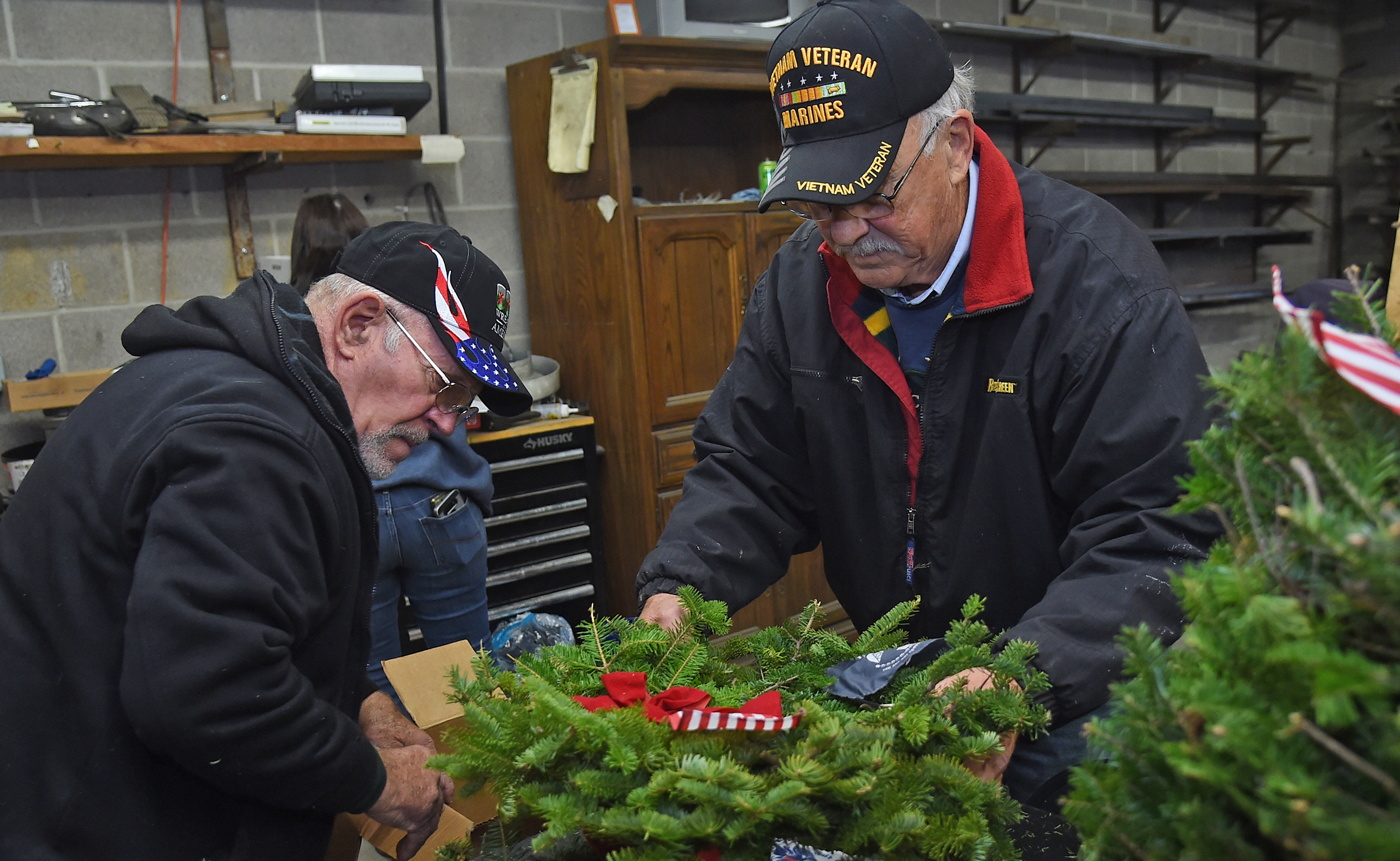 Volunteers Carroll Smith, left, an Army veteran, and Dan Cartzendafner, a Marine veteran, both of Union Bridge, pack finished ceremonial wreaths this morning at Babylon Vault Company in New Windsor. The wreaths were provided by Wreaths Across America, and will be placed on the graves of veterans in 47 cemeteries. Today, the volunteers decorated 376 wreaths. (Barbara Haddock Taylor/Staff)