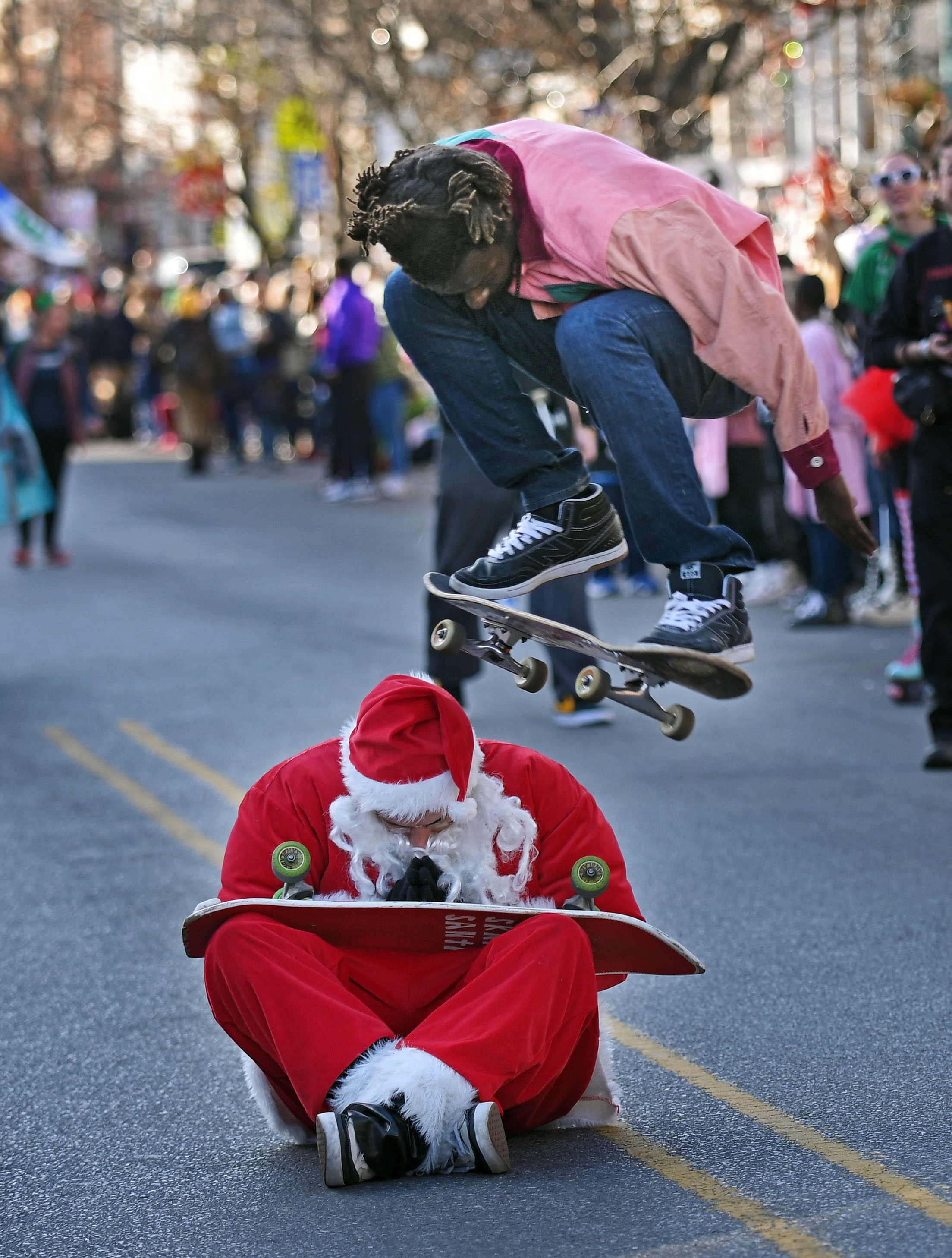 DC Wheels skateboarder Aaron Davis jumps over Jimmy Pelletier, the founder of DC Wheels, a non-profit group, on the parade route. The Mayor's Christmas Parade, an annual holiday celebration that captivates thousands along a 2.5-mile route through the Hampden and Medfield and neighborhoods. (Kenneth K. Lam/Staff)