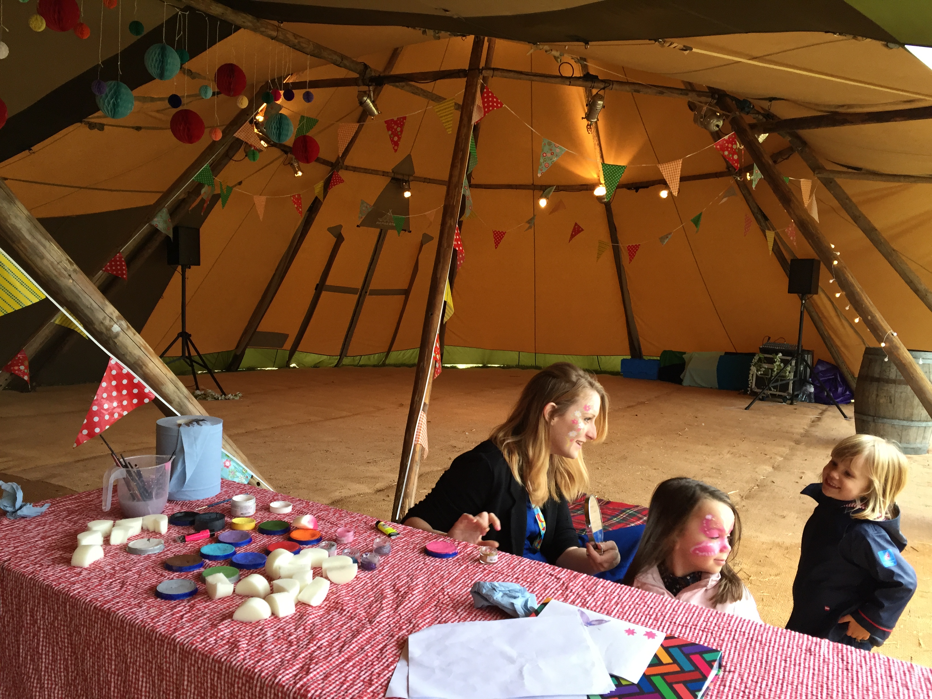 Face painter painting children's faces at party in Tipi
