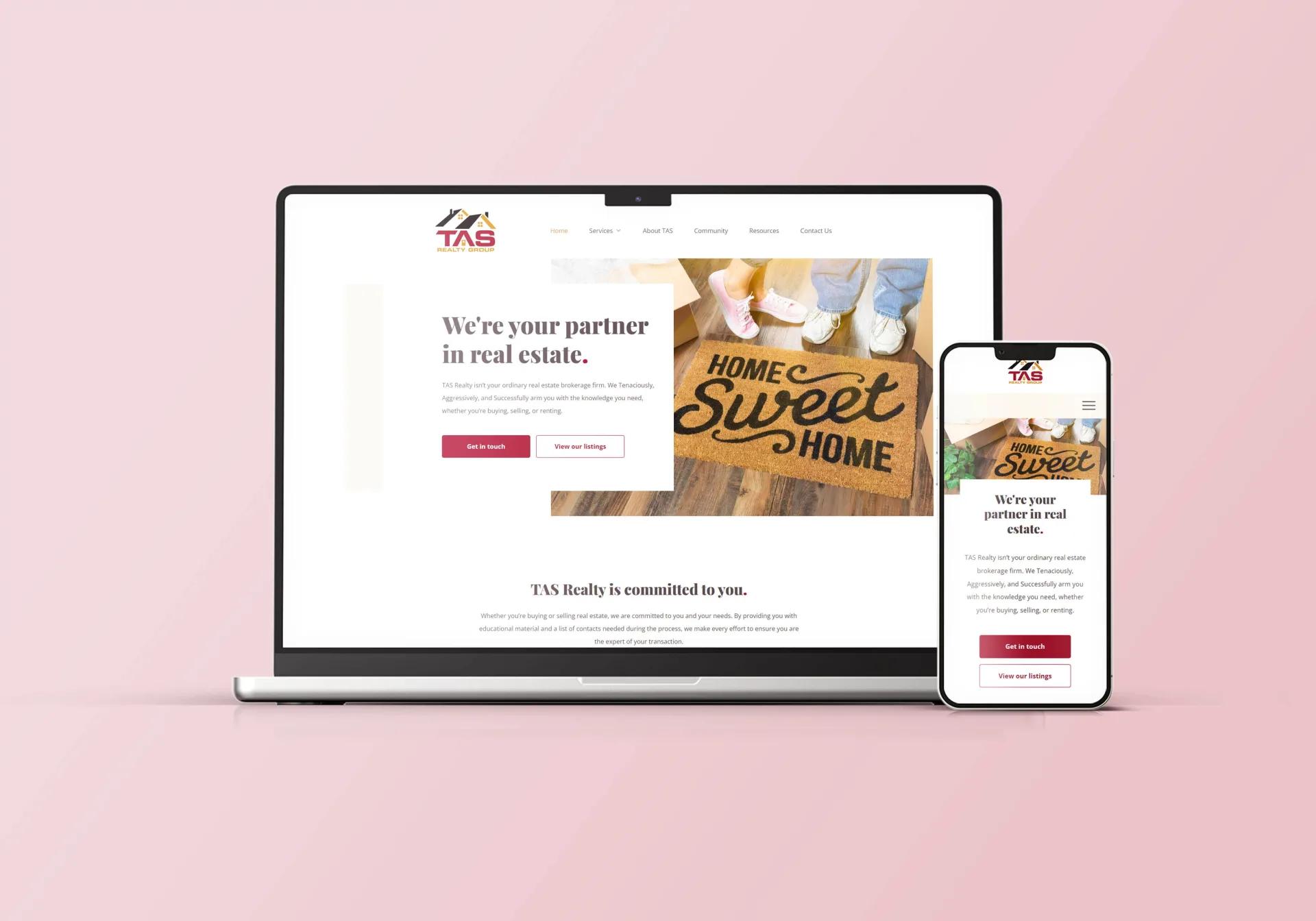 A laptop and a smartphone display the homepage of TAS Realty Group’s real estate website featuring the slogan “We’re your partner in real estate” and an image of feet by a “Home Sweet Home” doormat, all set on a pink background.