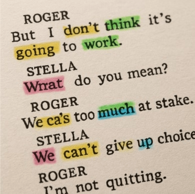 A close-up of a physical script page with different colored highlighter marks on various words.