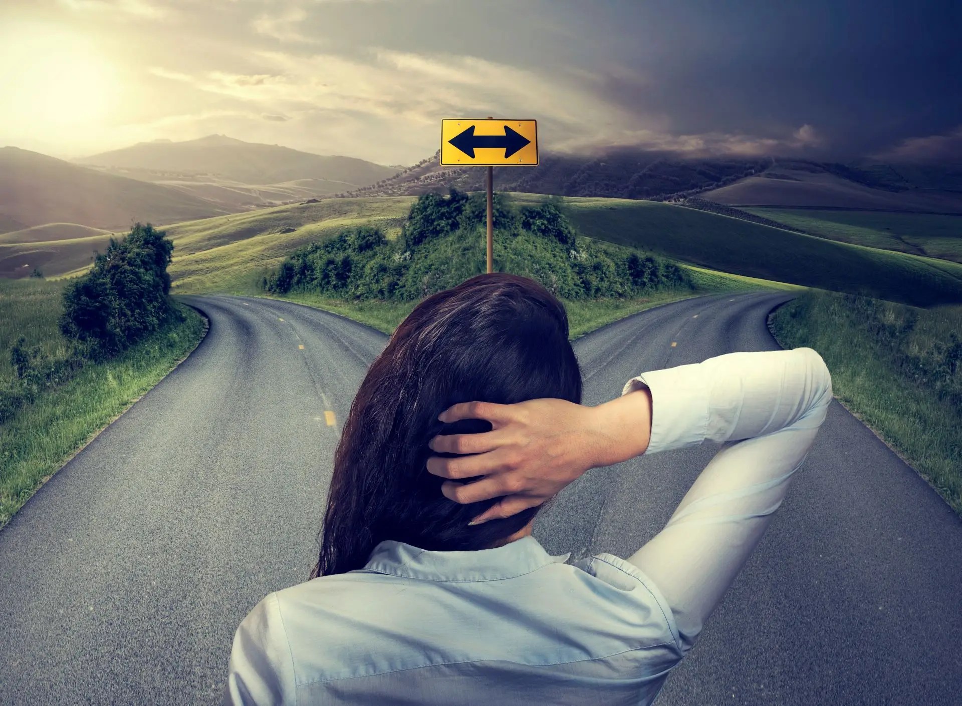Woman standing at a fork in the road, symbolizing a pivotal decision to face fear and choose personal growth in life and business.