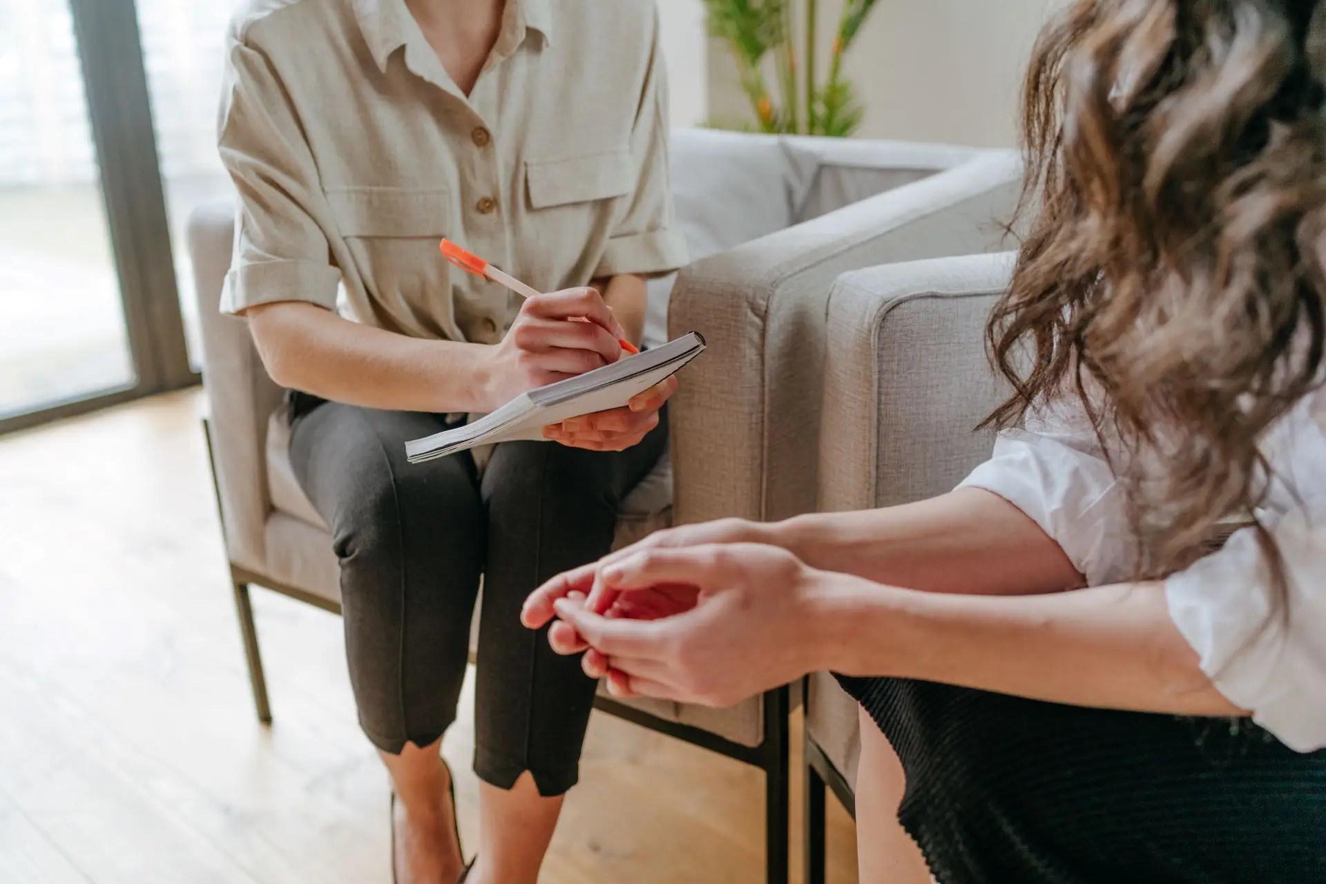 Two women in a coaching session, one taking notes while the other shares—symbolizing personalized support, strategy, and work-life clarity.