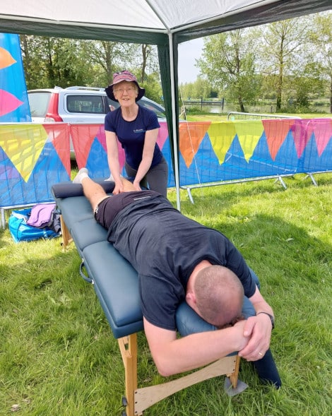 Therapist massaging a leg at an outside running event.
