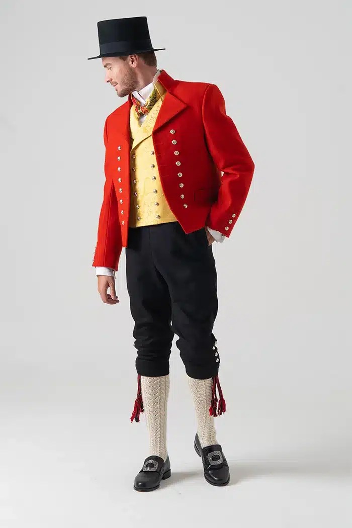 Mann i full Vestfoldbunad med hatt, viser sølvknappene og detaljene mens han ser til siden.