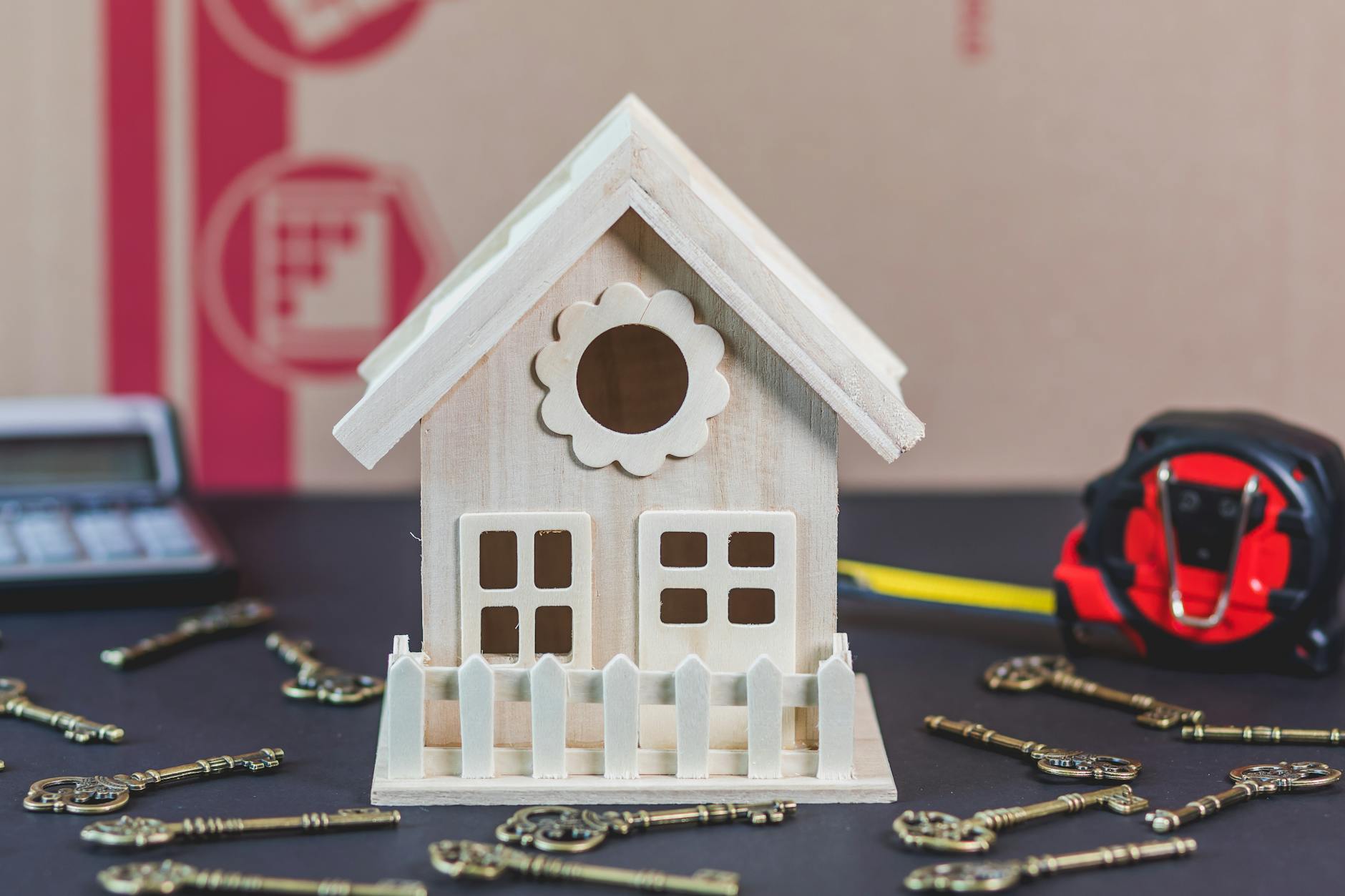 white wooden miniature house surrounded by vintage keys on a black surface