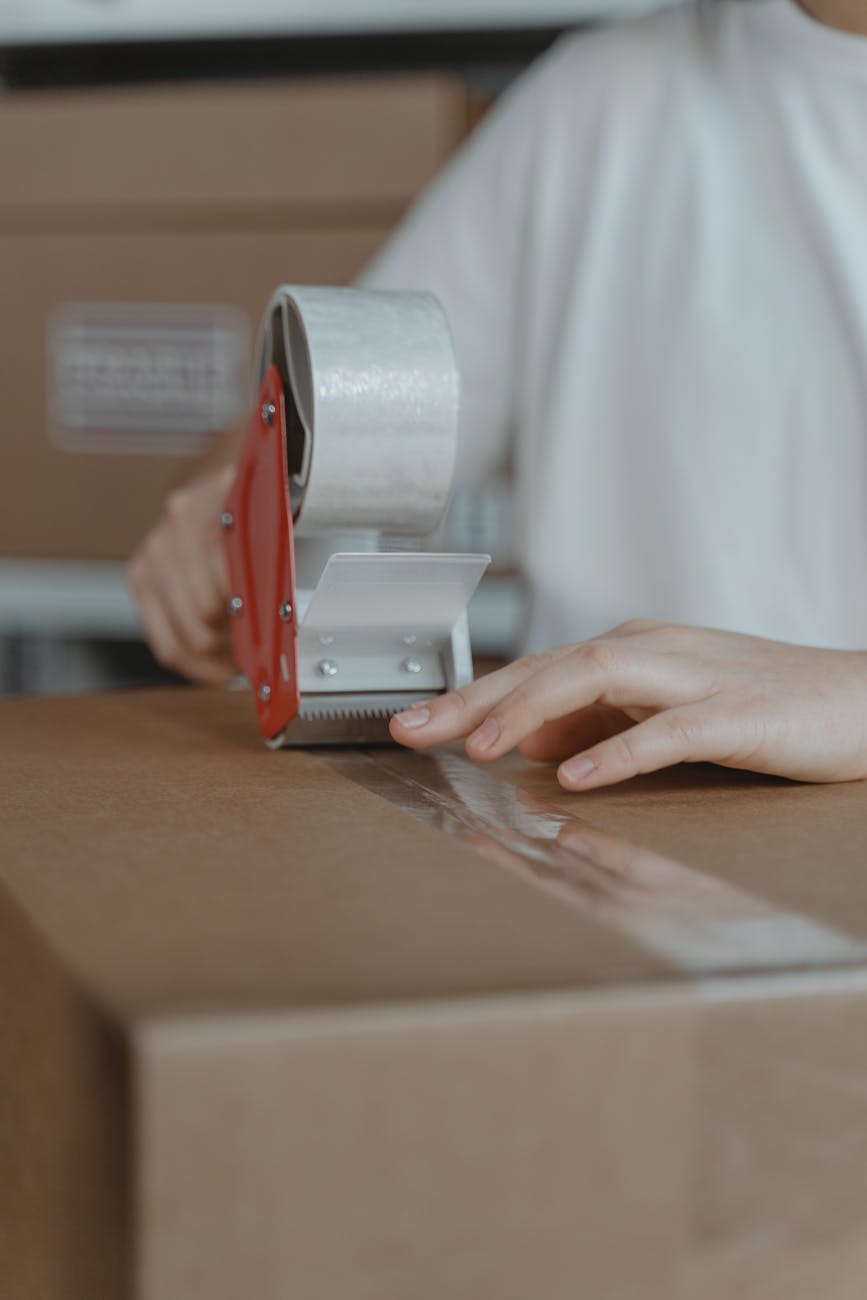 person putting tape on a cardboard