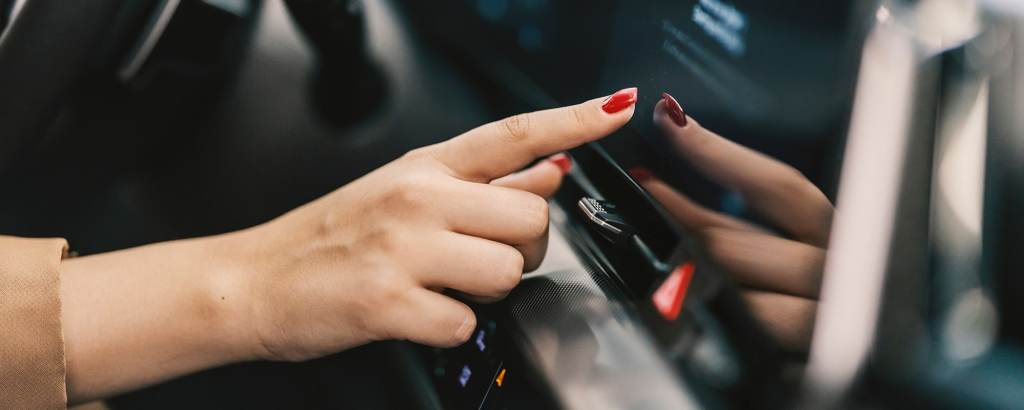 Close up of a female hand pressing touch screen in car.