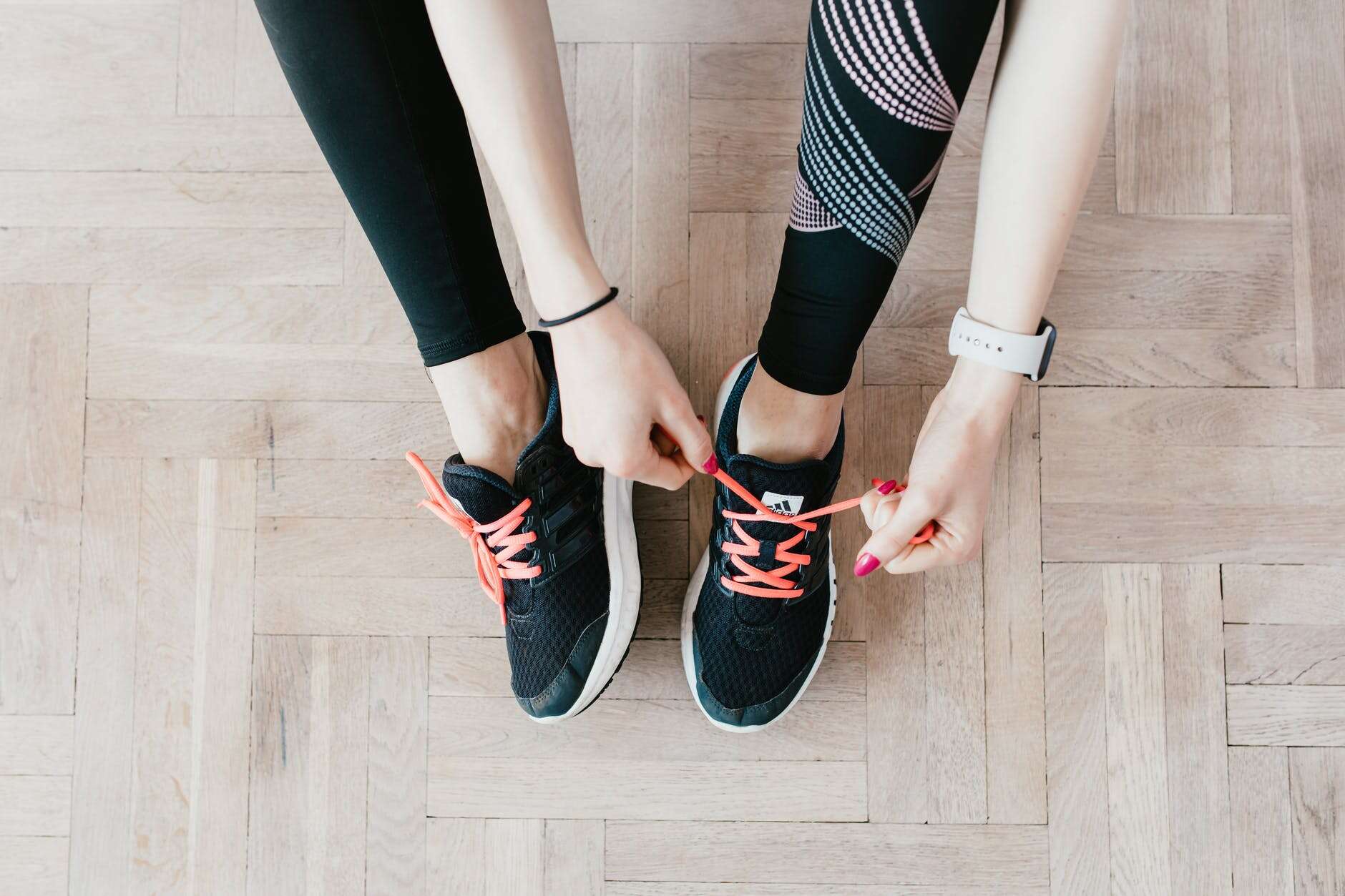 crop young sportswoman tying sneakers on floor