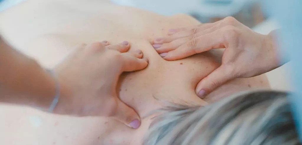 physical therapist massages a patients back as a tool for relieving back pain