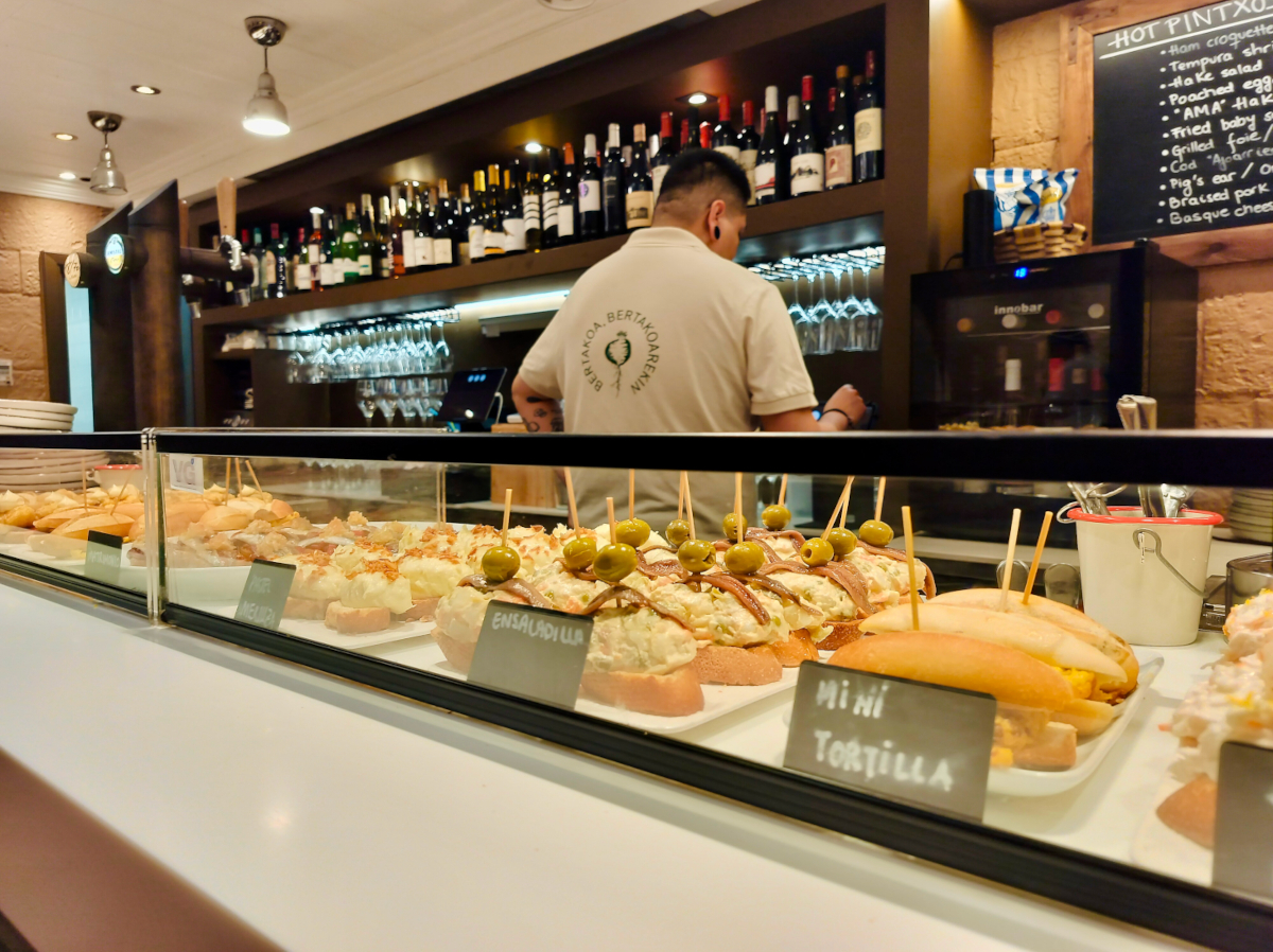 Looking along the bar in Bertakoteka, a pintxos bar in San Sebastián. The counter has a selection of fresh cold pintxos, and