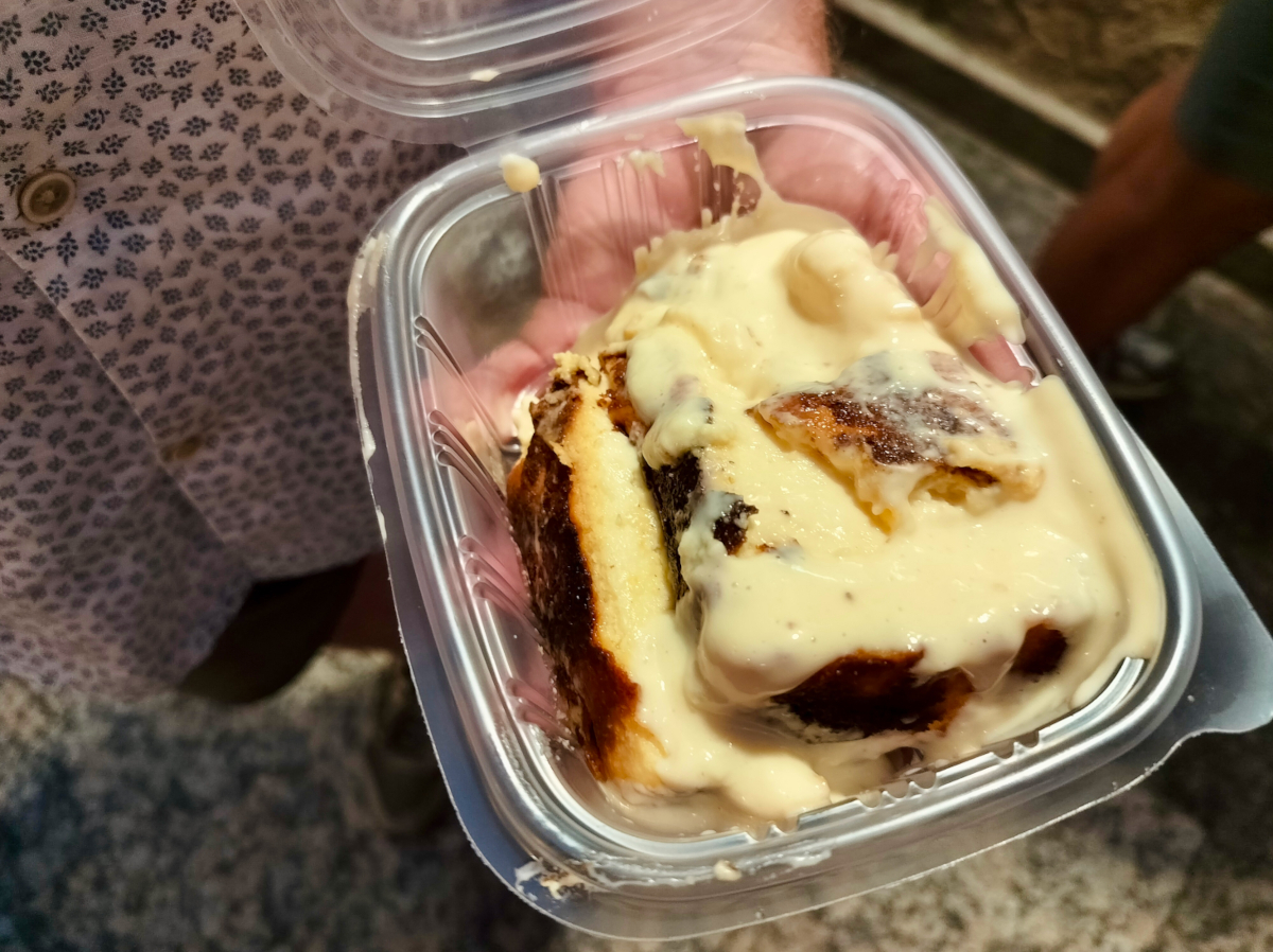 A plastic container containing a portion of basque cheesecake with gravy.